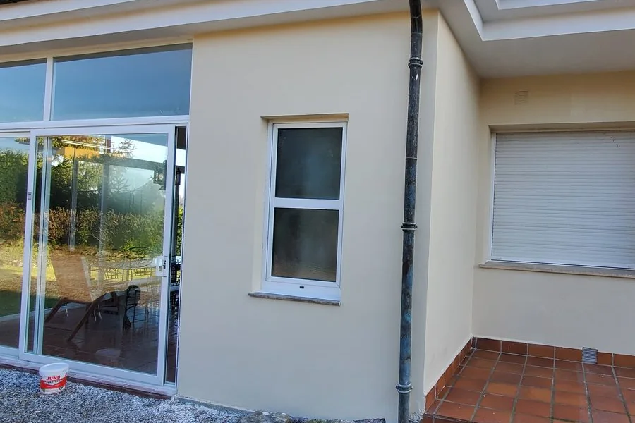 Fachada de una vivienda en La Guía, Gijón, con el revoco lucido y pintado en tono crema