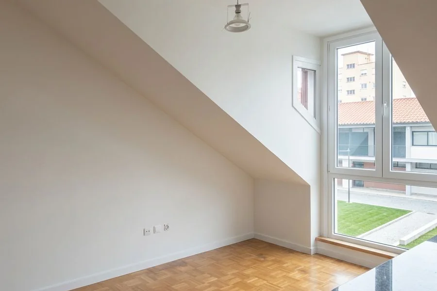 Habitación bajo cubierta con las paredes recién pintadas en un piso de Gijón