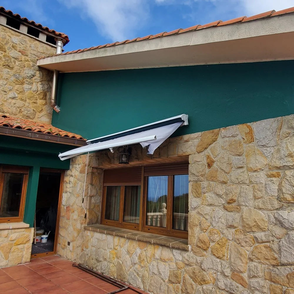 Chalet con la fachada pintada en verde, con esquinas y zócalo de piedra y un porche con balaustrada