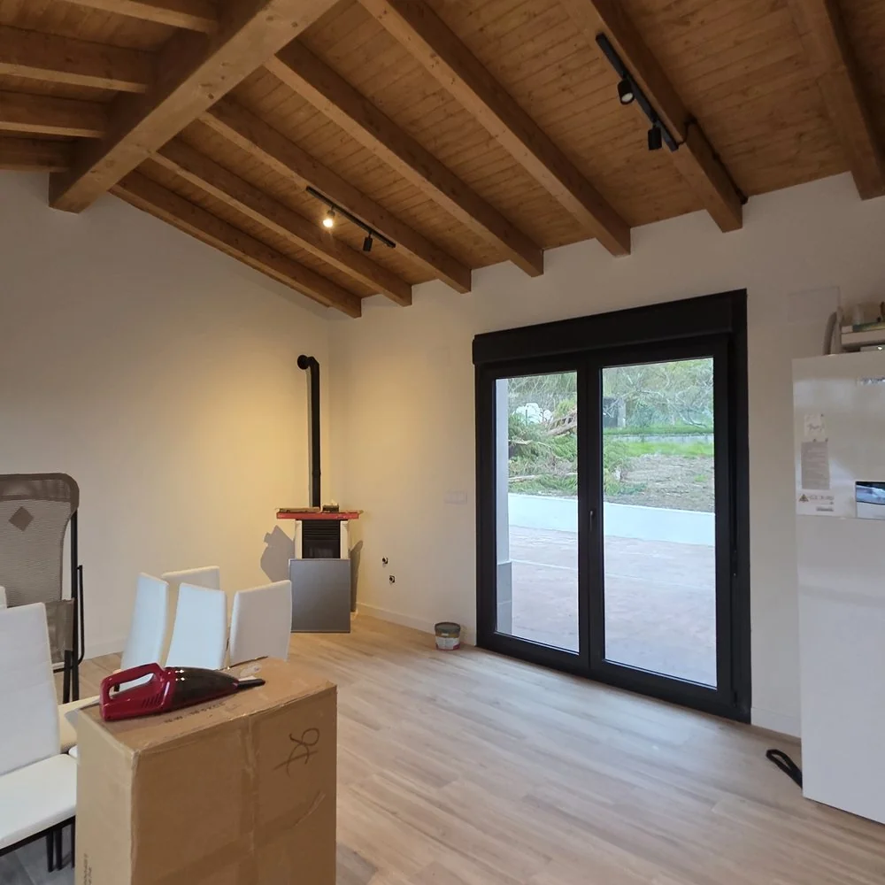 Comedor de una vivienda unifamiliar con techo de madera, paredes blancas y salida a la terraza