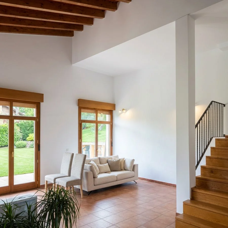 Salón de una casa con vigas de madera y paredes blancas en Fano, Gijón