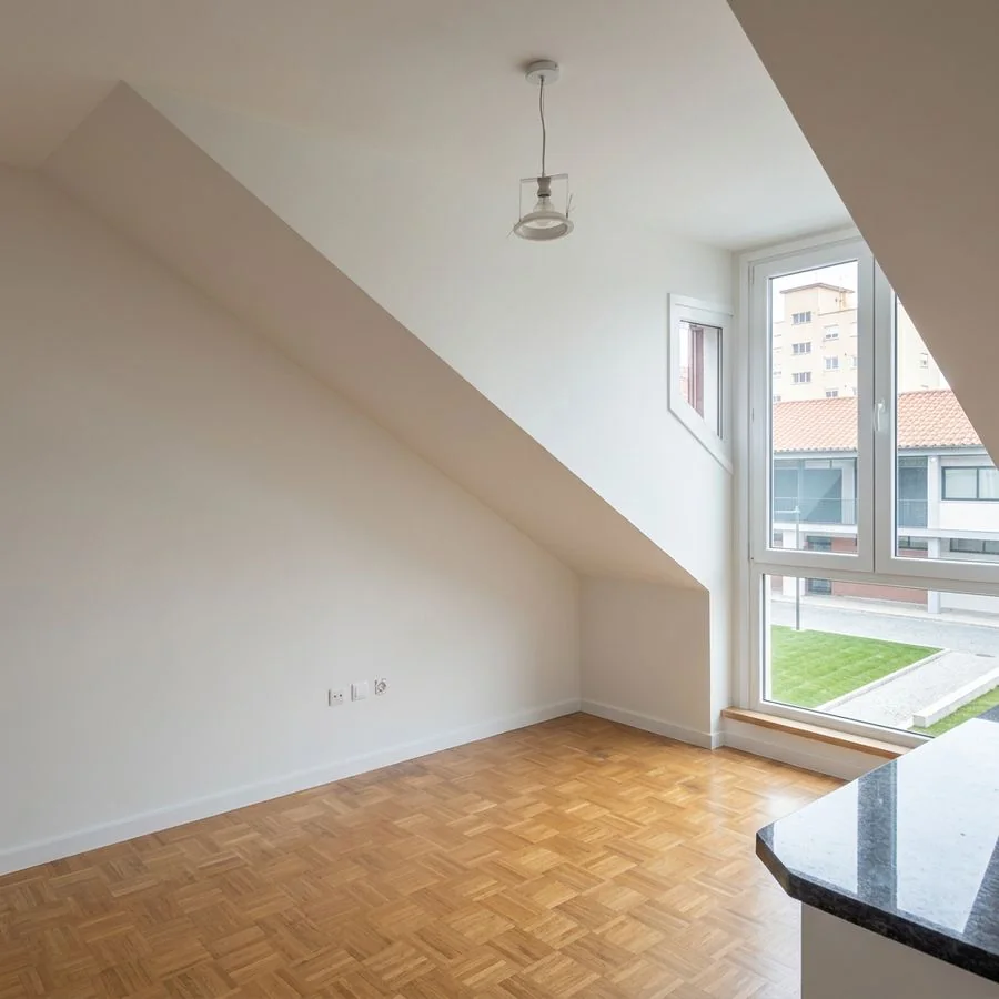Habitación bajo cubierta con paredes blancas y suelo de parqué en Gijón